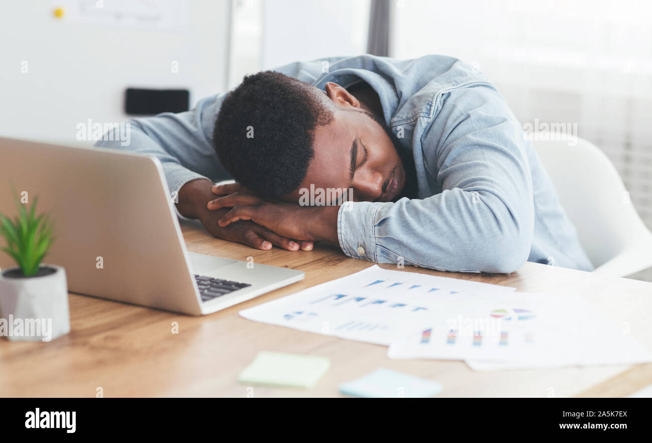 Überarbeitet afrikanische amerikanische Mitarbeiter schlafen am Arbeitsplatz im Büro Stockfoto