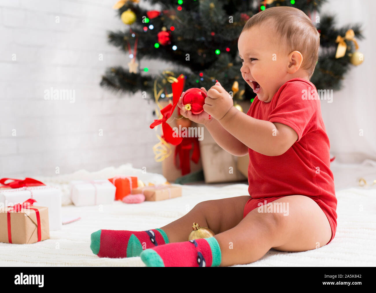 Wütend emotionale Baby schreien, Sitzung mit Dekorationen in der Nähe von Weihnachten Baum Stockfoto