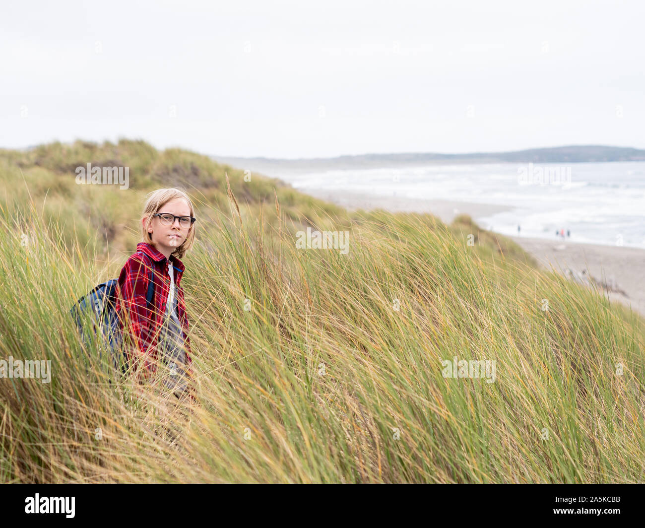 Tween Boy auf Kamera stehen in hohen Meer Gras an der Küste Stockfoto