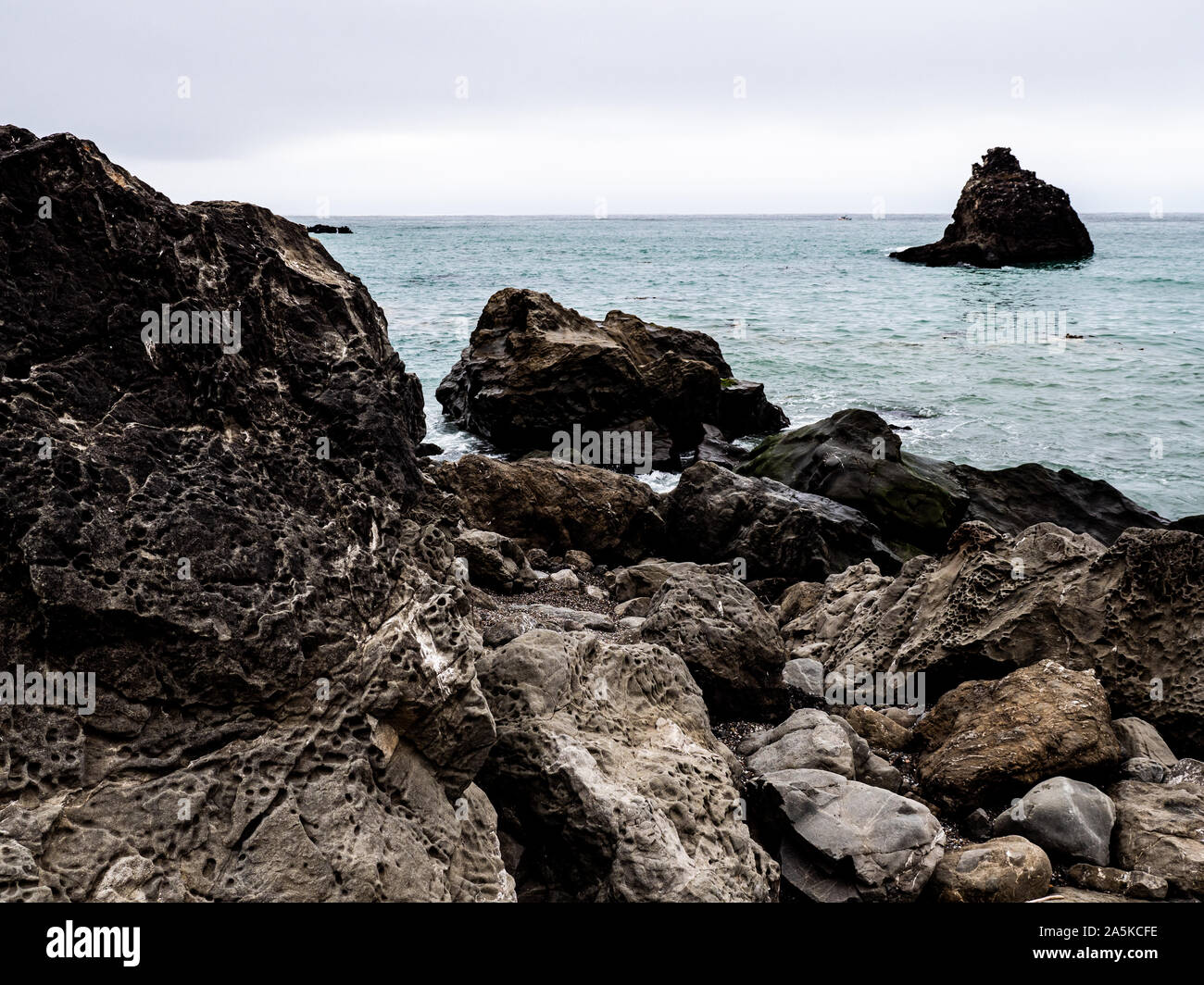 Felsenküste mit großen verwitterten Steinen bedeckt die Textur Stockfoto