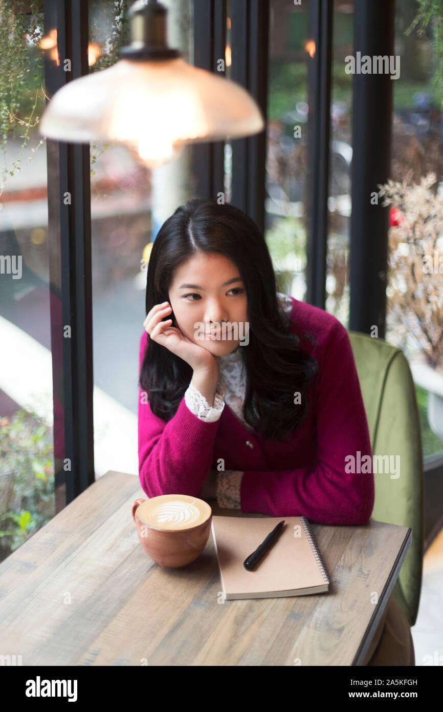 Frau sitzt an den hölzernen Tisch im Cafe Stockfoto