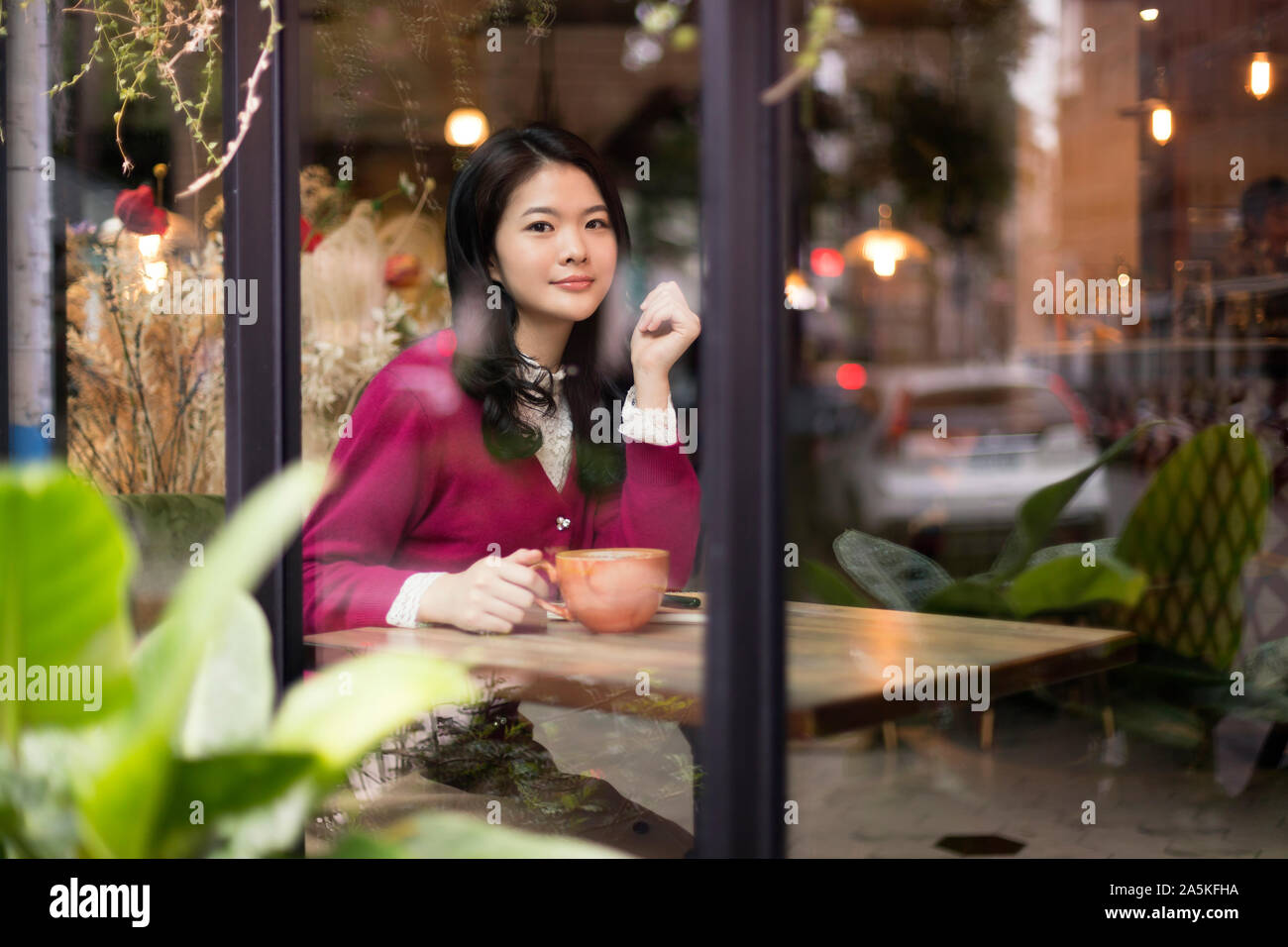 Frau sitzt an den hölzernen Tisch im Cafe Stockfoto