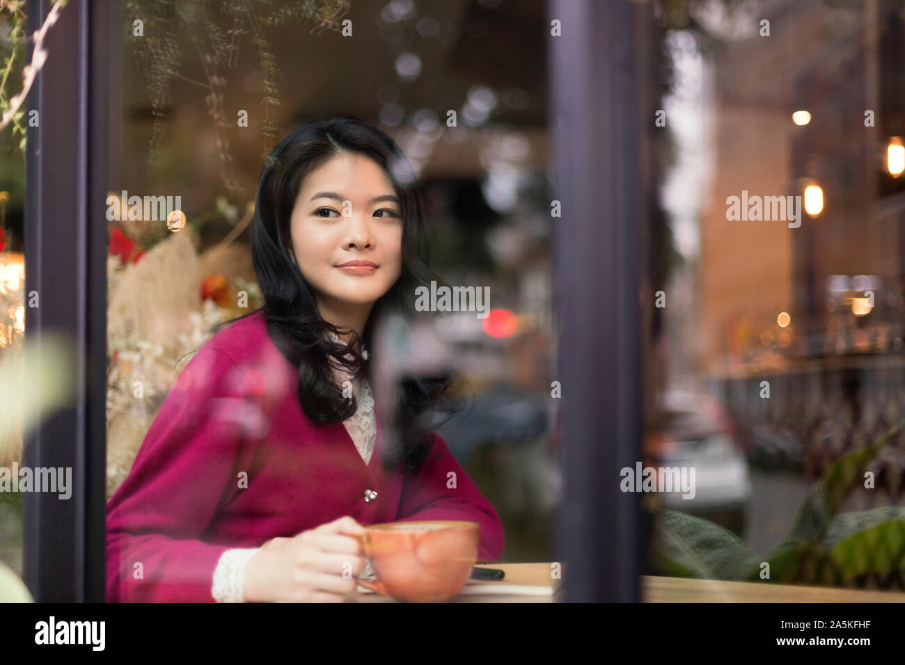 Frau sitzt im Cafe und schauen durch das Fenster Stockfoto