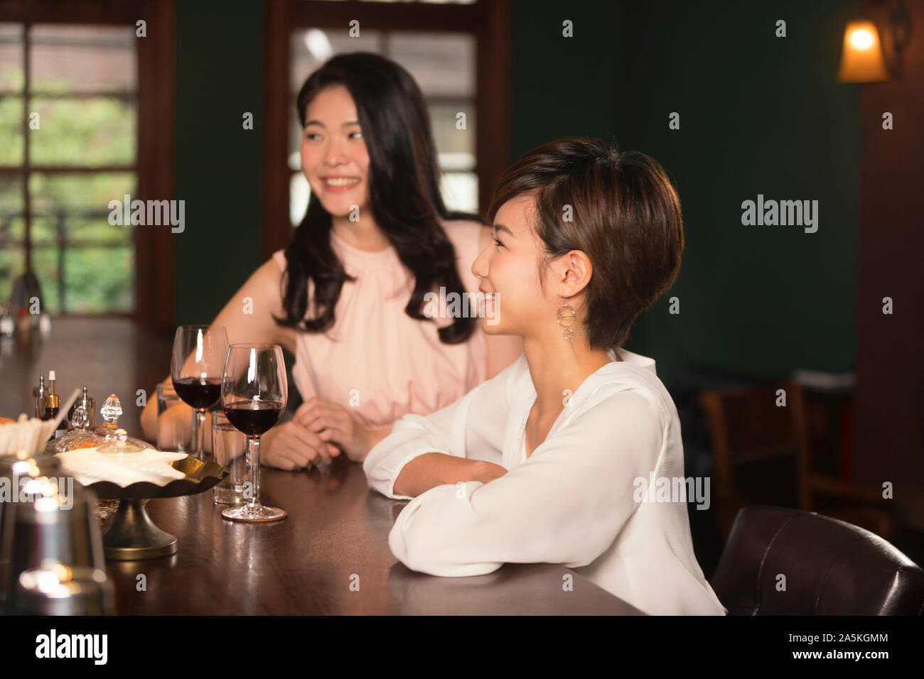 Zwei Frauen in Wein, während an der Theke sitzen in bar Stockfoto