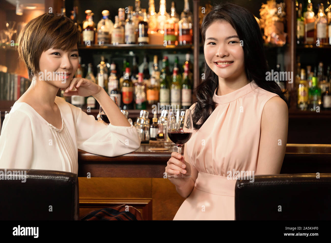 Porträt von zwei jungen Frauen mit Rotwein an der Theke Stockfoto