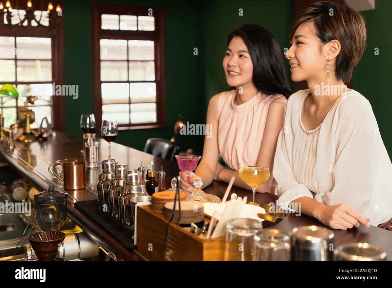 Zwei lächelnde junge Frauen entspannen und Cocktails an der Bar Counter Stockfoto