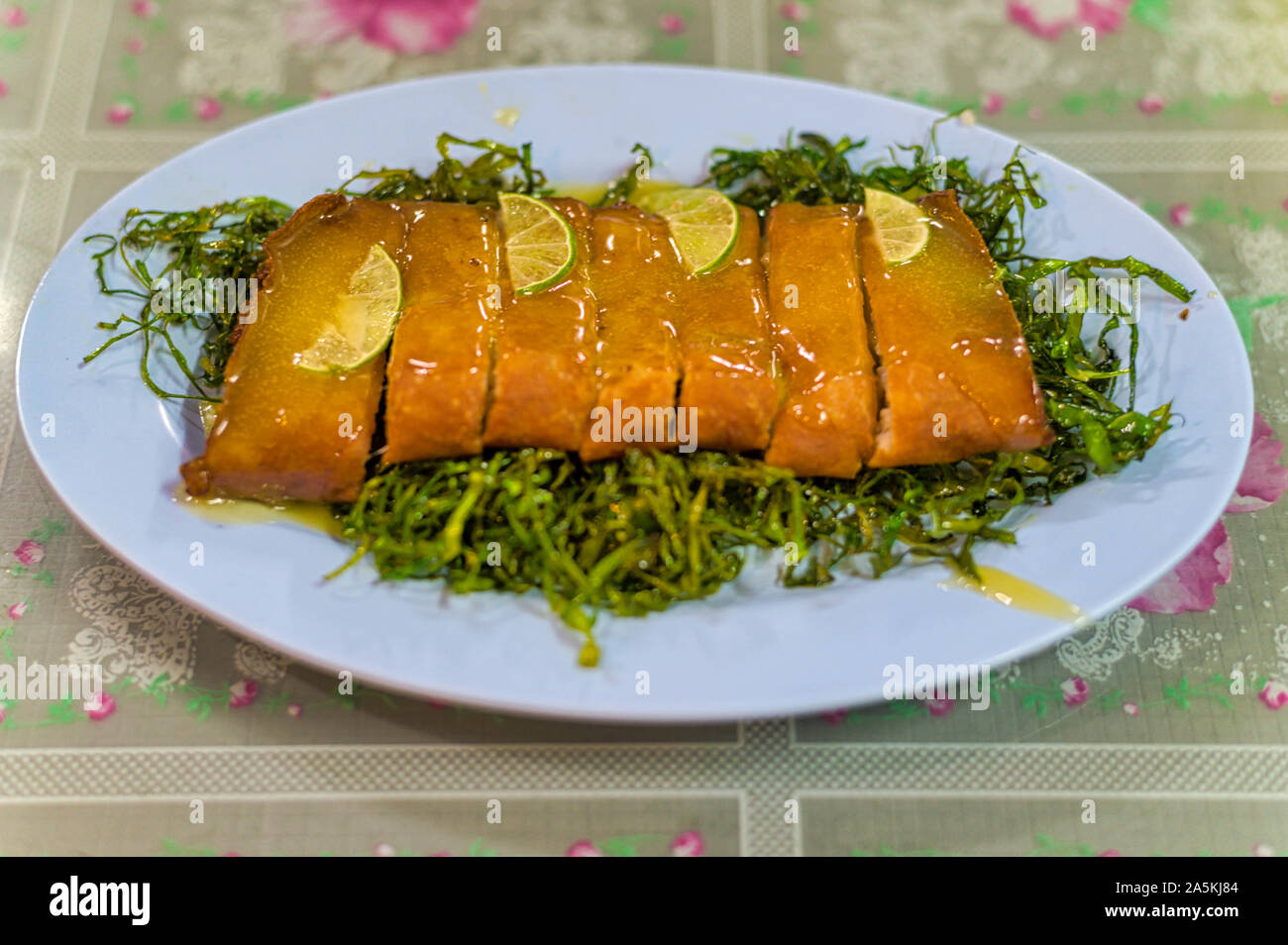 Gebratenes Schweinefleisch mit Zitronensauce und Zitrone Stücke, mit geschredderten Kaffernlimette Blätter knackig Grün. Stockfoto