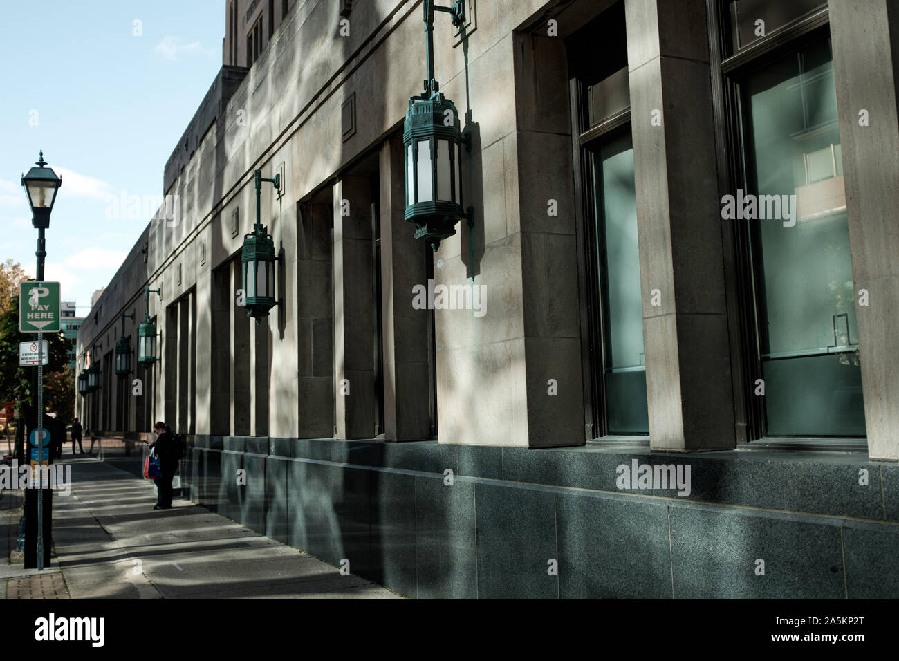 London, Kanada - 18. Oktober 2019. Eine Frau überprüft Ihr Telefon vor einem Gebäude, das Sonnenlicht auf sie nieder. Stockfoto