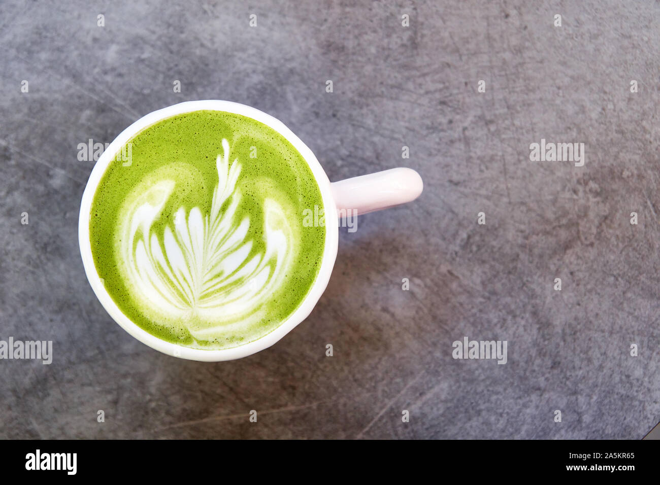 Vegan grüner Tee mit Matcha Hafermilch mit Latte Art in weißen Schale auf konkrete Tabelle. Ansicht von oben, mit Platz für Text. Stockfoto