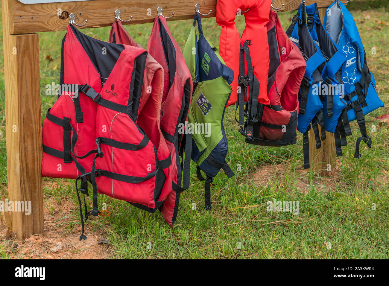 Verschiedene Schwimmwesten aller Größen hängen für den Einsatz am See Stockfoto