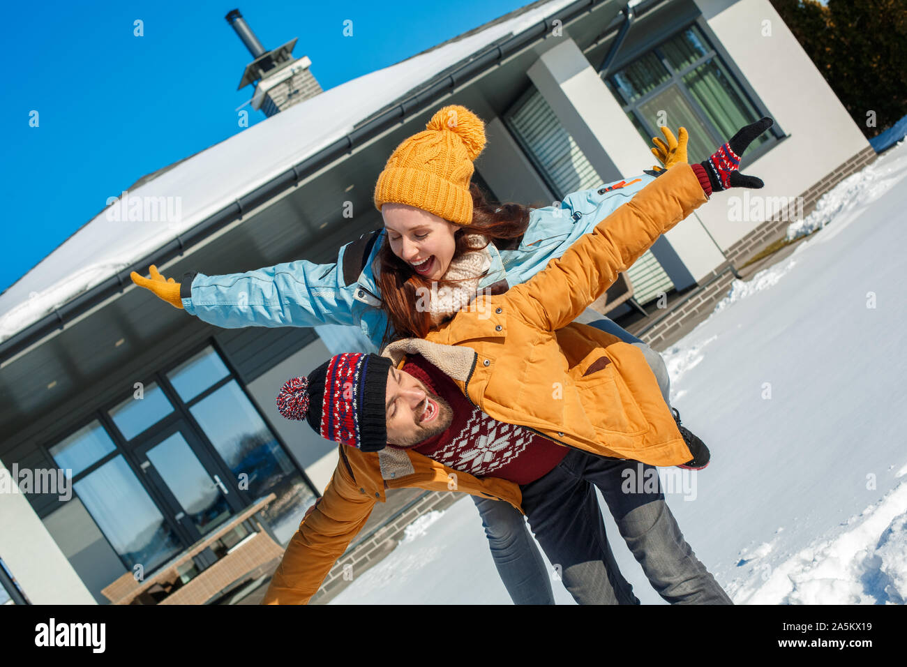 Winter Urlaub. Junges Paar stehen gemeinsam im Freien in der Nähe von Haus fliegen stellen Lachen verspielt Stockfoto