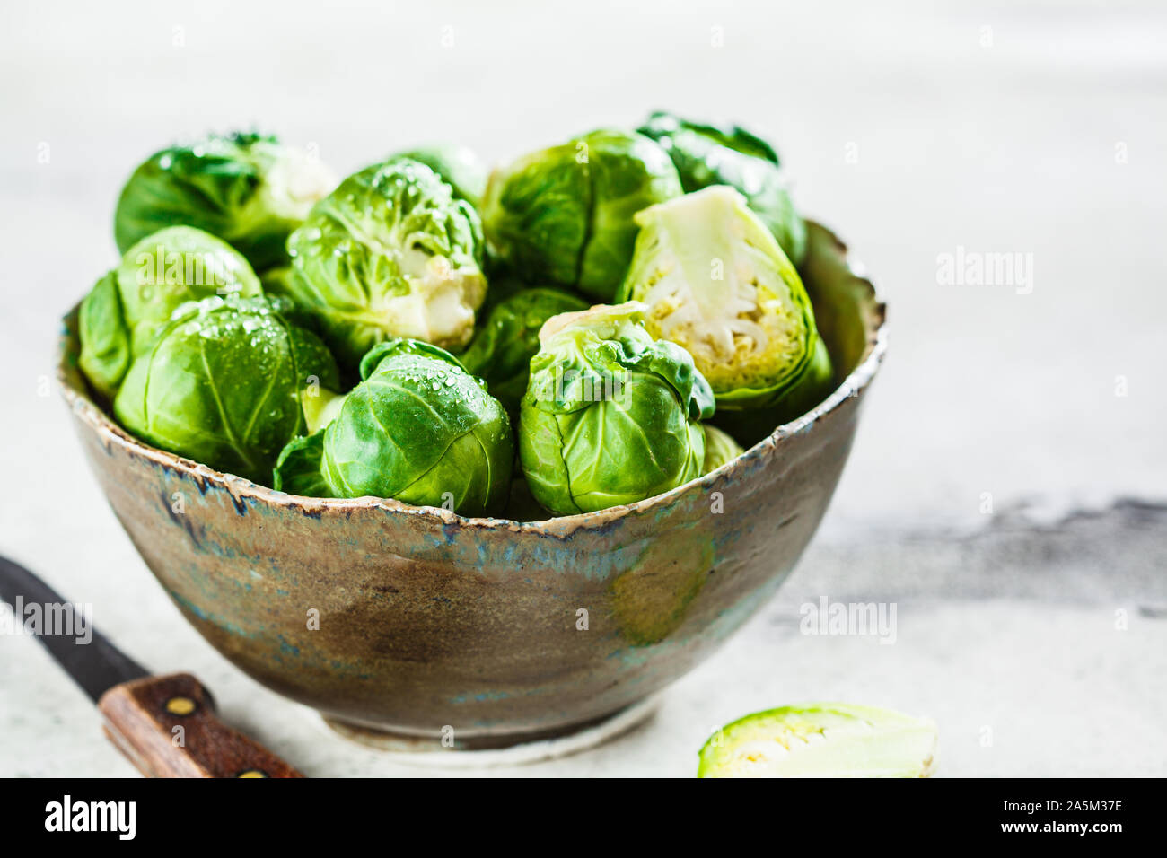 Raw Rosenkohl in eine Schüssel, grau konkreten Hintergrund. Gesunde vegane Ernährung Konzept. Stockfoto