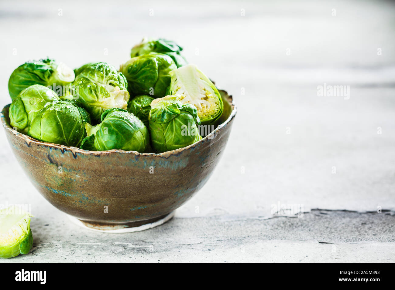 Raw Rosenkohl in eine Schüssel, grau konkreten Hintergrund, kopieren. Gesunde vegane Ernährung Konzept. Stockfoto