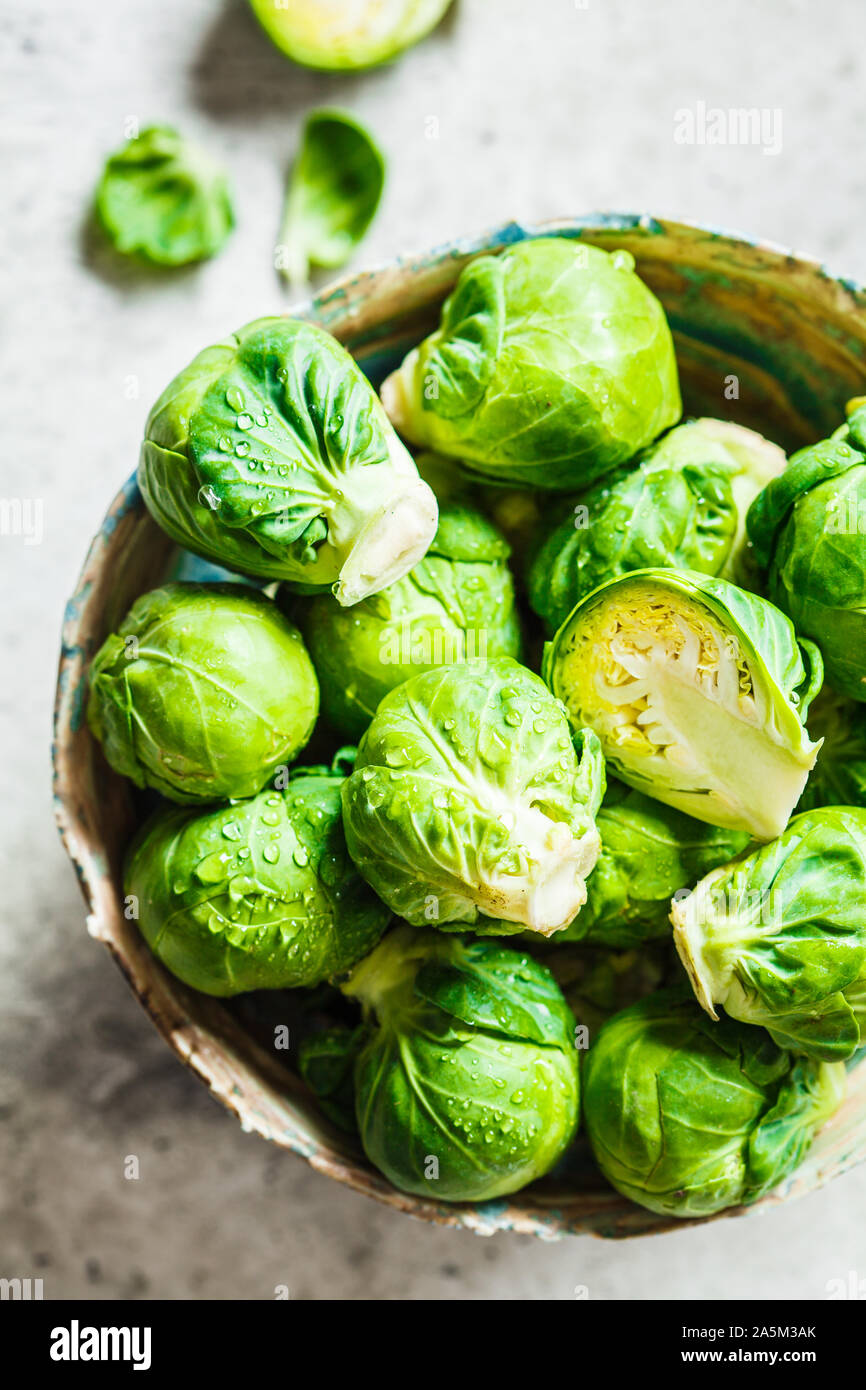 Raw Rosenkohl in eine Schüssel, grau konkreten Hintergrund. Gesunde vegane Ernährung Konzept. Stockfoto