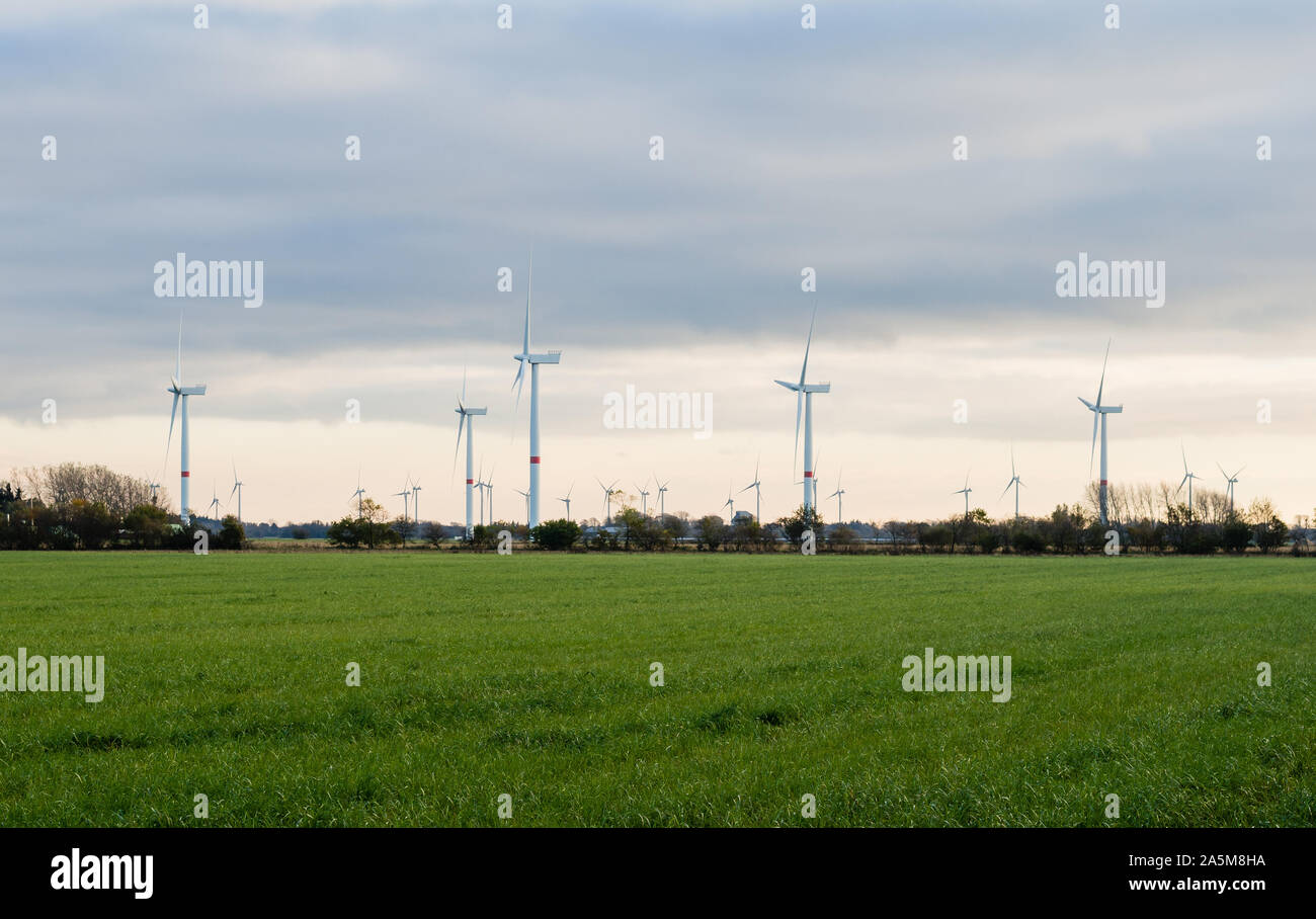 Windenergieanlagen oder Windmühlen Strom aus Windkraft auf der grünen Wiese bei Sonnenuntergang, Nordfriesland, Deutschland. Stockfoto