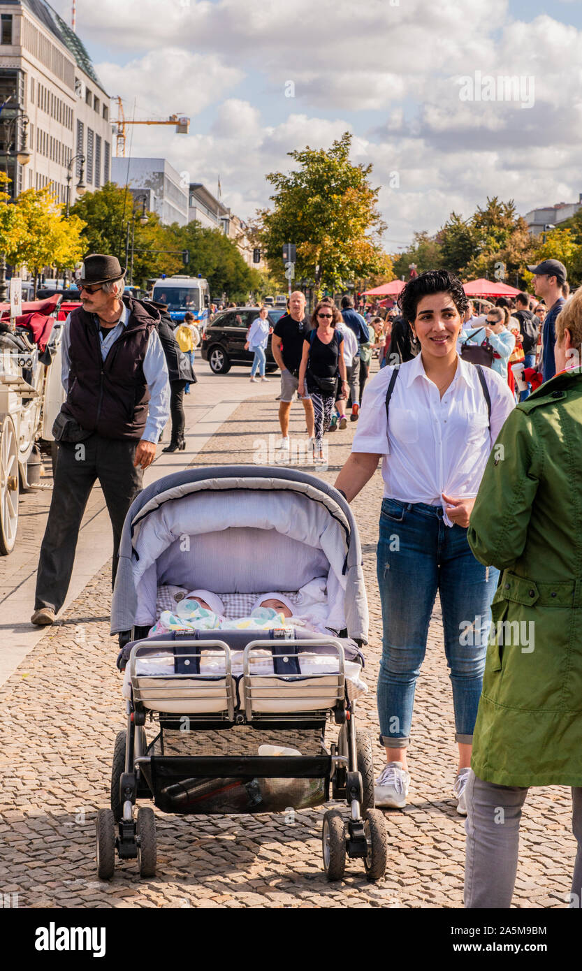 Tourist mit Babys, die in der Beförderung im Gespräch mit Freund auf der belebten Promenade, Bundastag, Berlin, Deutschland, Großbritannien Stockfoto