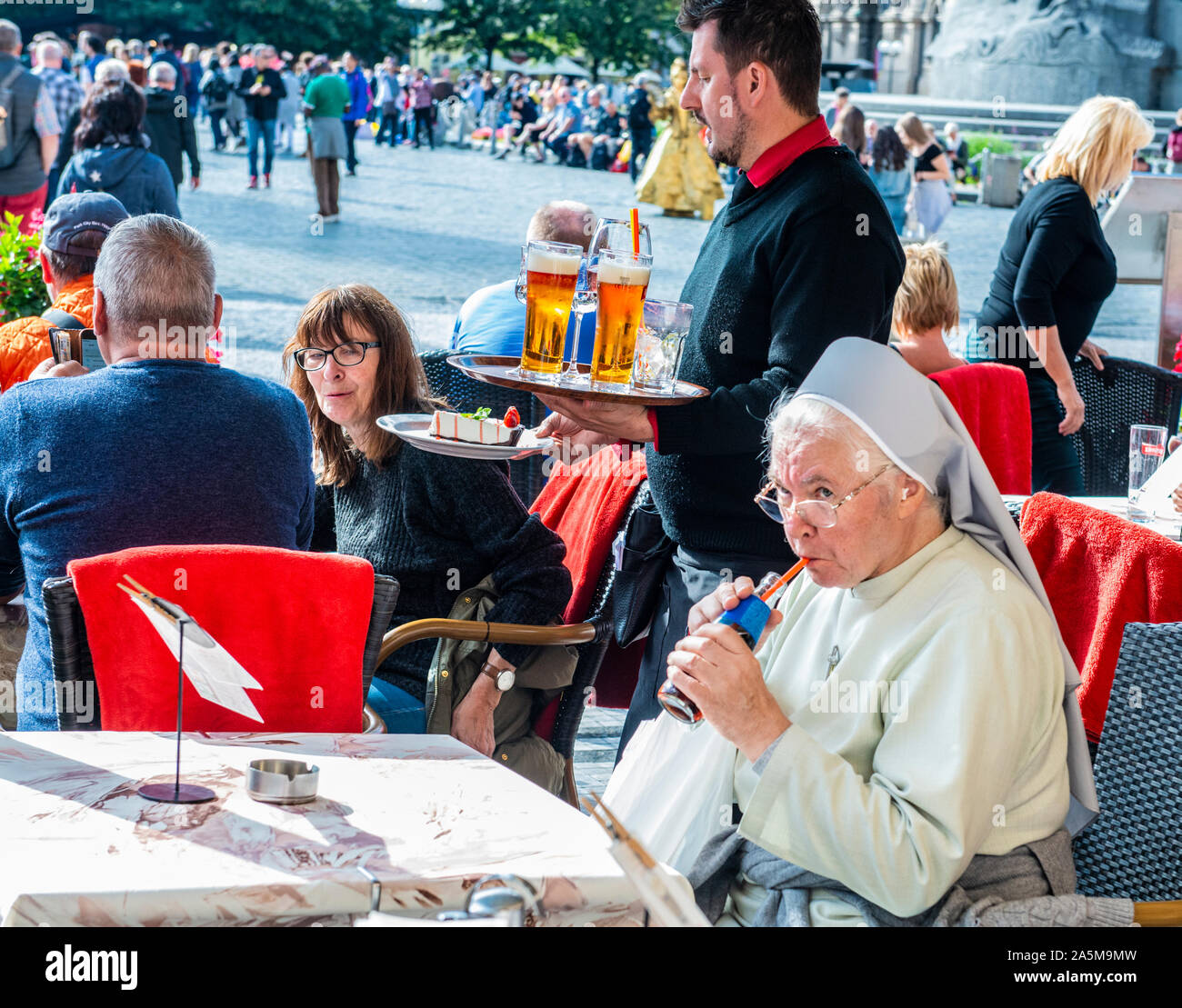 Nonne und Touristen trinken und essen im Straßencafé, Altstädter Ring, Prag, Tschechische Republik Stockfoto
