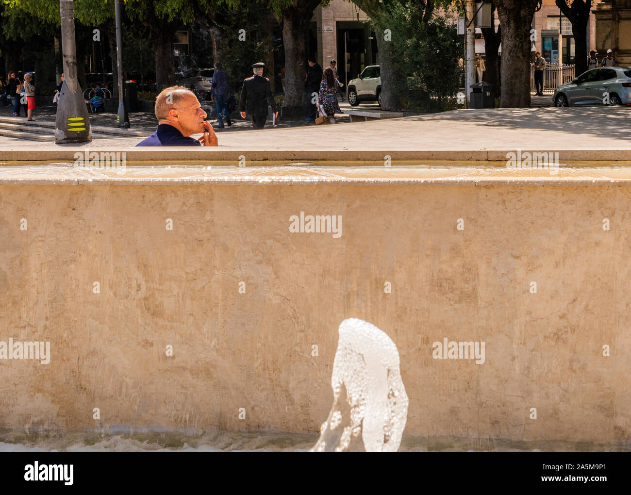 Mann hinter Betonmauer in die Ferne suchen, Piazza Risorgimento, Avezzano, Abruzzen, Italien Stockfoto
