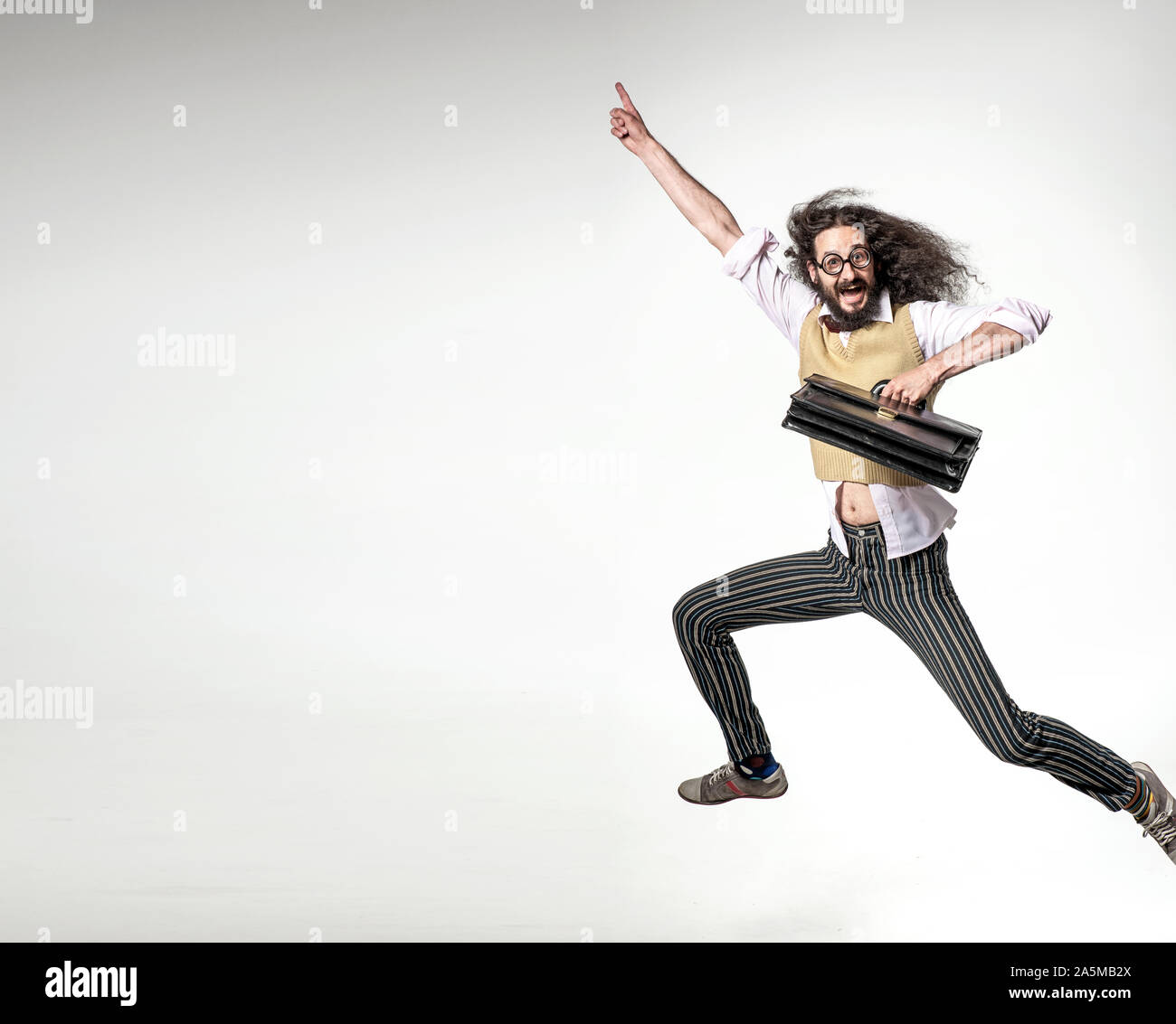 Nerdy Mann mit einer Aktentasche und springen über der Tafel im Hintergrund Stockfoto