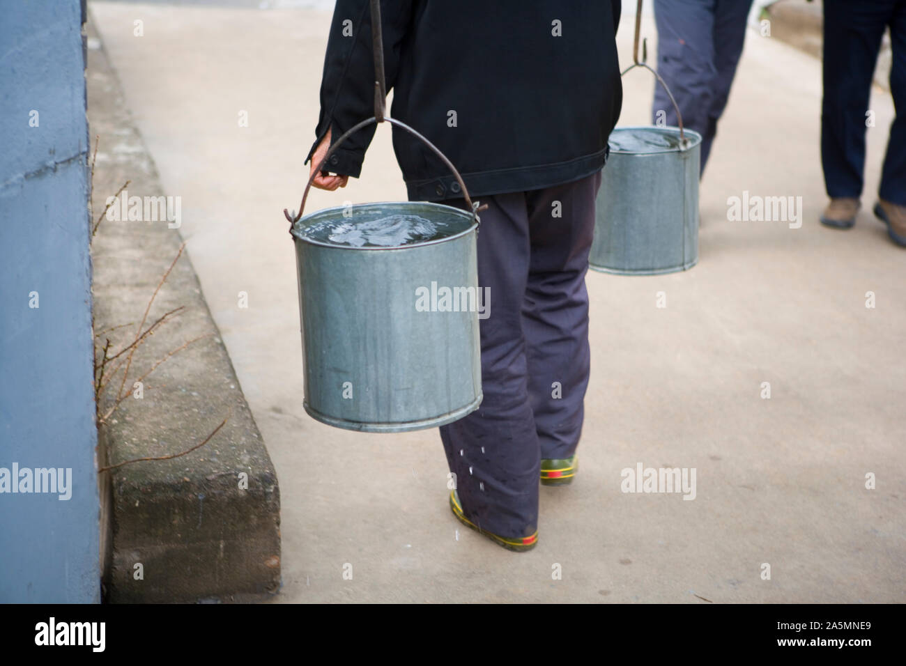 Person, die großen Eimer Wasser. Stockfoto