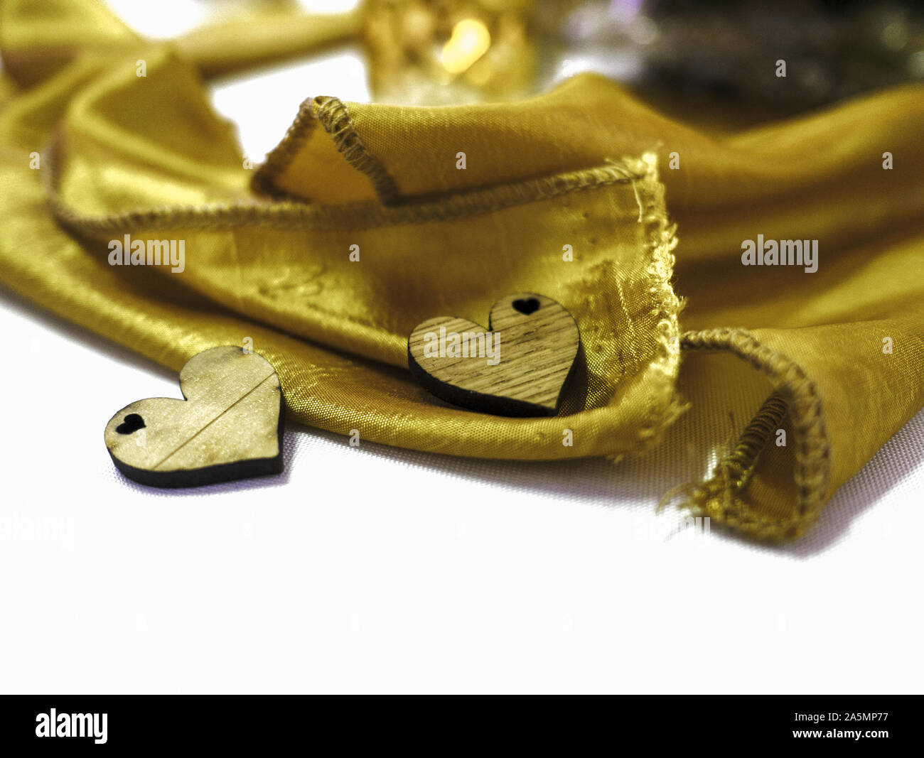 Zwei Holz geschnitzt Herzen auf Tabelle mit gelben satin Serviette Stockfoto