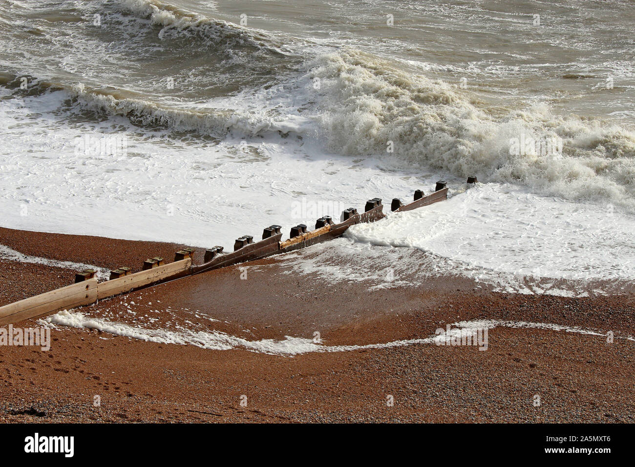 Diese hölzernen Buhnen dienen als Verteidigung gegen die erodierende Wirkung von Wellen auf dem Kiesstrand. Foto in Bexhill, East Sussex, England. Stockfoto