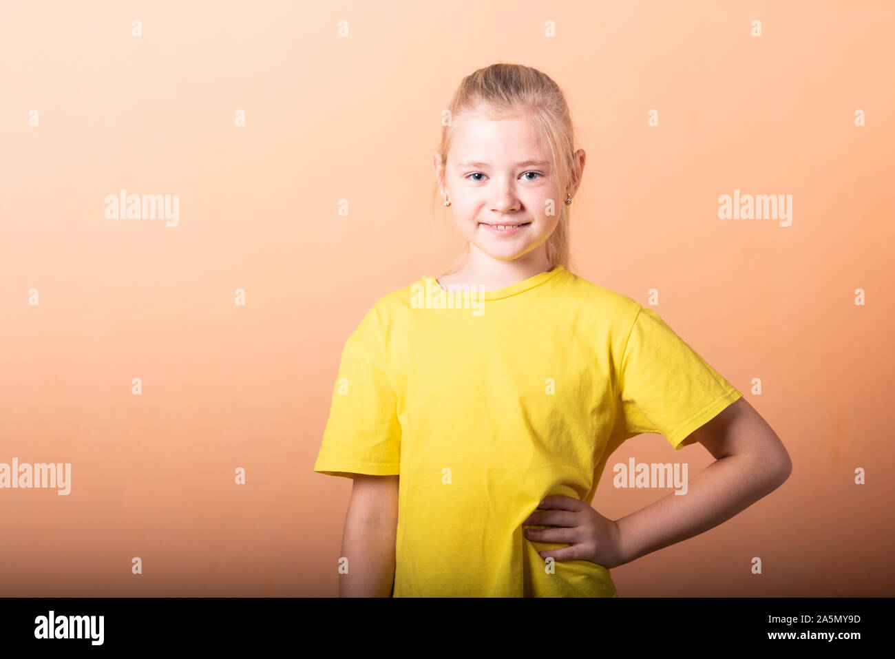 Das Mädchen legte ihre Hände auf ihren Hüften, auf einem hellen orange hinterlegt. Stockfoto