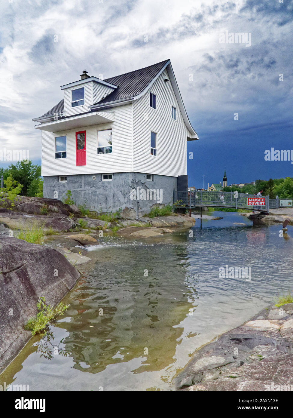 Die berühmten kleinen weißen Haus (La Petite Maison Blanche) in Saguenay, dass die Überschwemmungen 1996 widerstanden, mit stürmischen Himmel über Stockfoto
