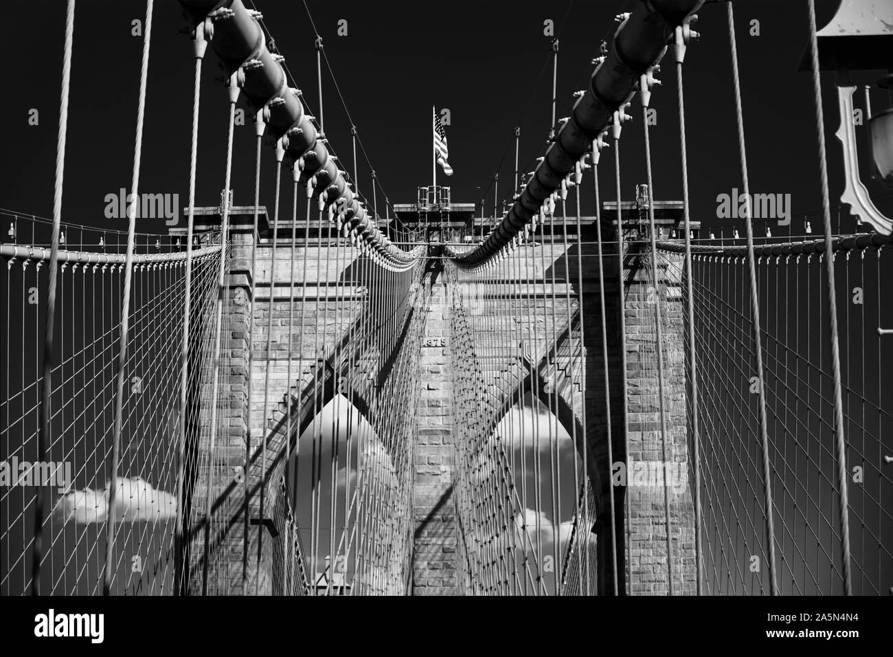 Low Angle View eines steinernen Turm mit Stahlseilen und die US-Flagge, Brooklybn Bridge, New York City Stockfoto