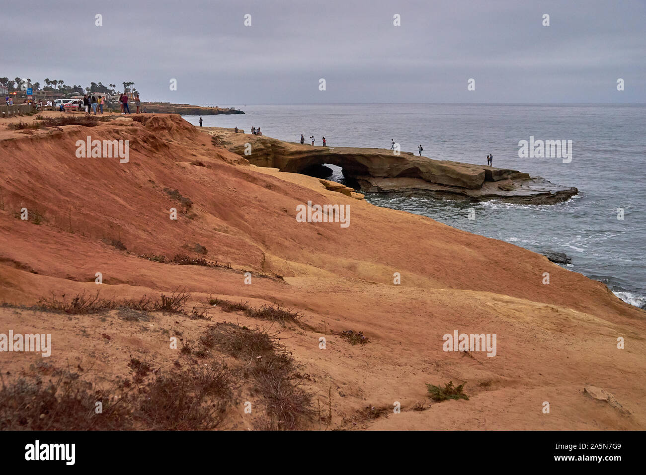 Eine Vielzahl von Menschen, Touristen, einschließlich ein Paar, Stehen, Laufen oder Sitzen am Strand und Klippen am Sunset Cliffs, San Diego, Kalifornien Stockfoto