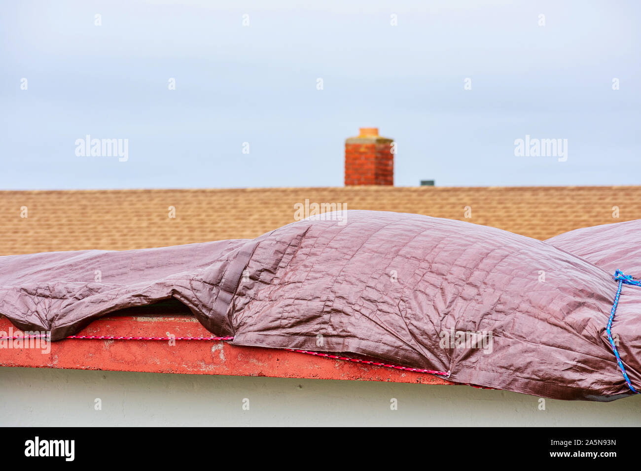 Wasserdichte tarp Abdeckung am Dach auf einem flachen, undicht, beschädigte Dach als Notfall, temporäre Haus Schutz ein Gebäude von der weiteren Regen Schäden zu speichern. Stockfoto