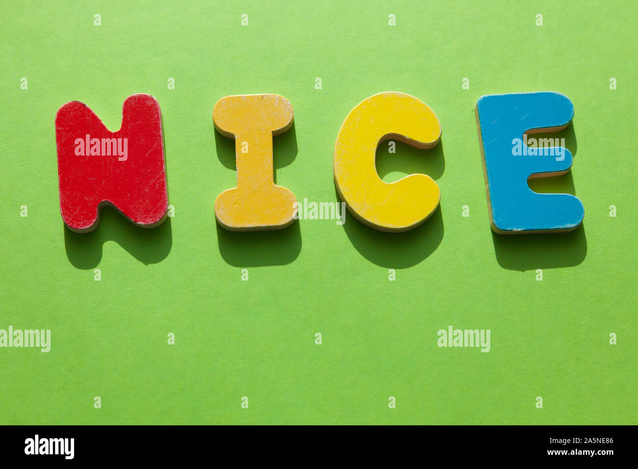 Das Wort schön in Holz Buchstaben liegt auf einer grünen Fläche Stockfoto