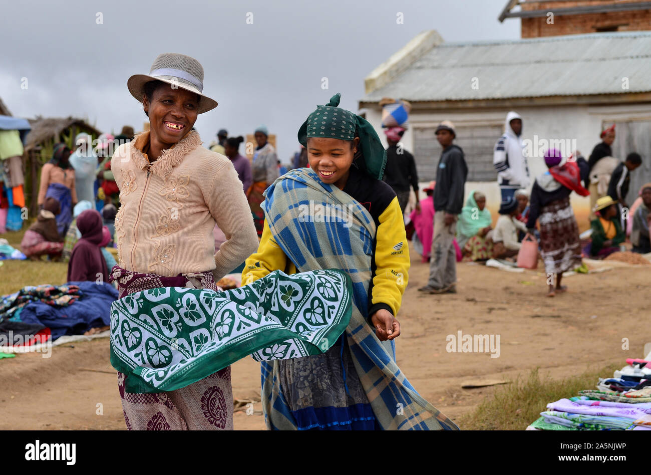 Zwei madagassische Frauen lächelnd, während für den Verkauf von Kleidung in einem Markt. In der Nähe von Ambositra, zentralen Madagaskar Stockfoto