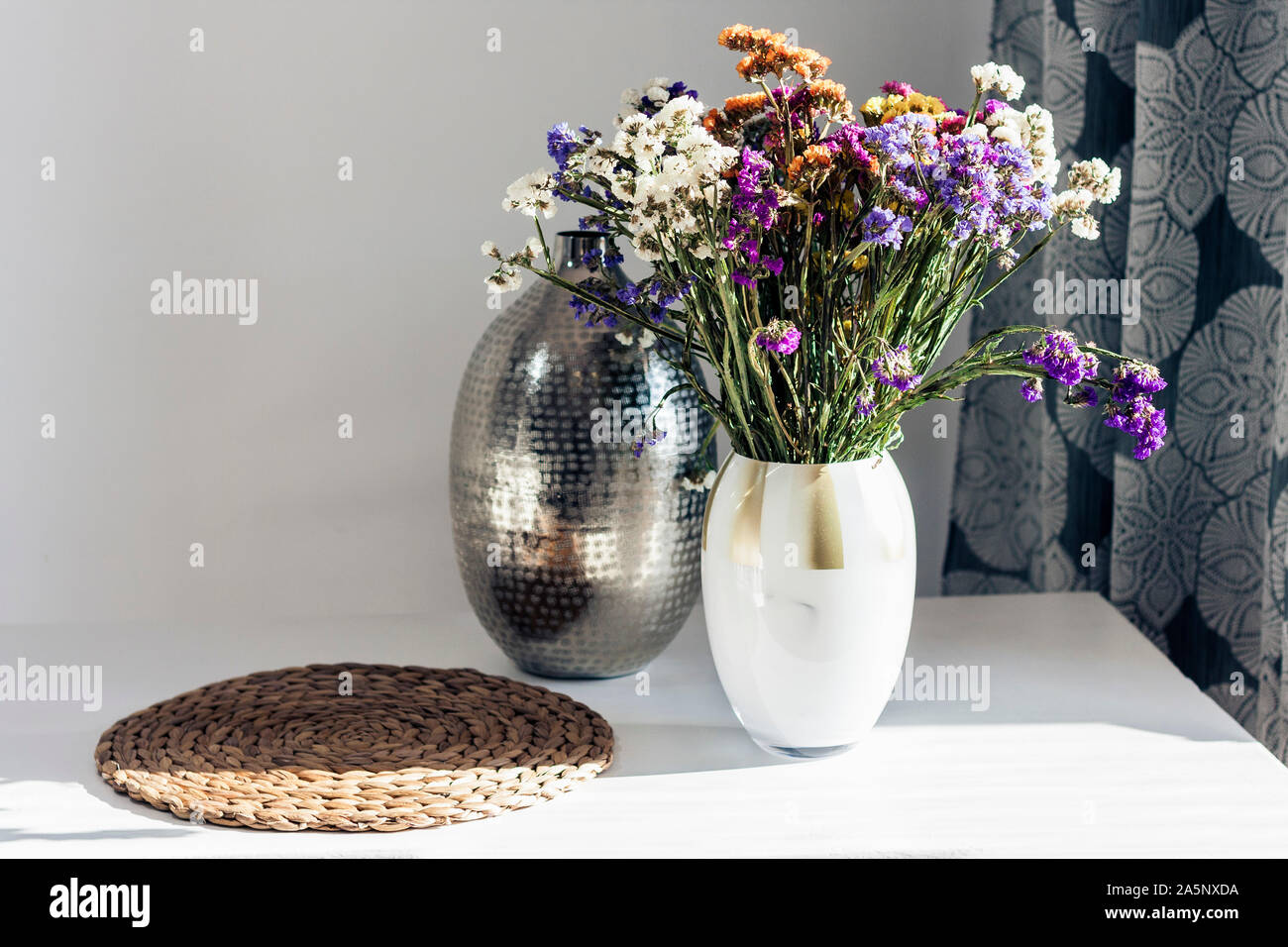 Blumenstrauß, Metall Vase und Stroh Weide stehen auf dem Tisch, gemütliche Interieur Stockfoto