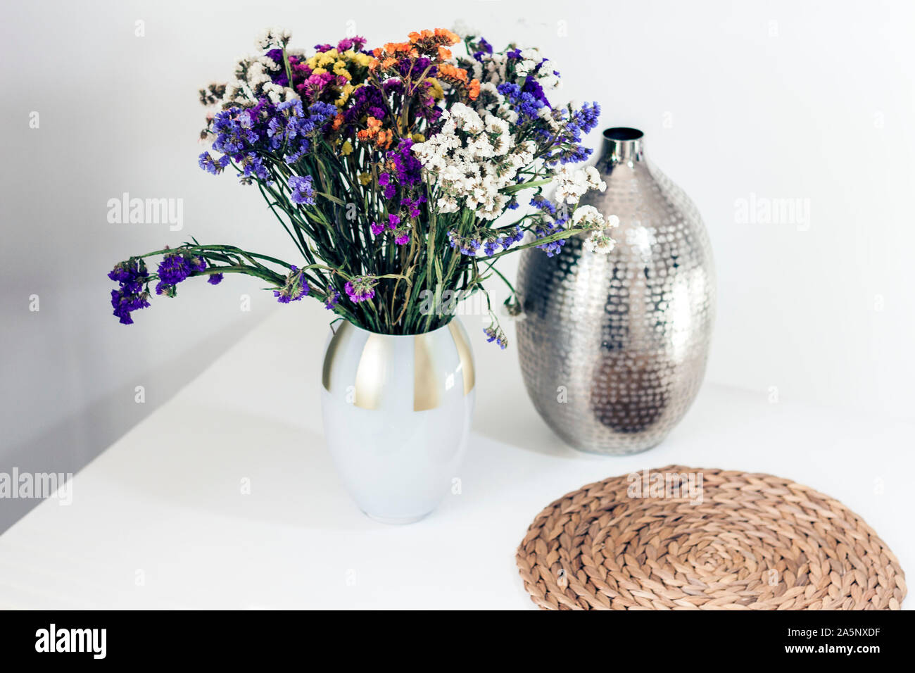 Blumenstrauß, Metall Vase und Stroh Weide stehen auf dem Tisch, gemütliche Interieur Stockfoto