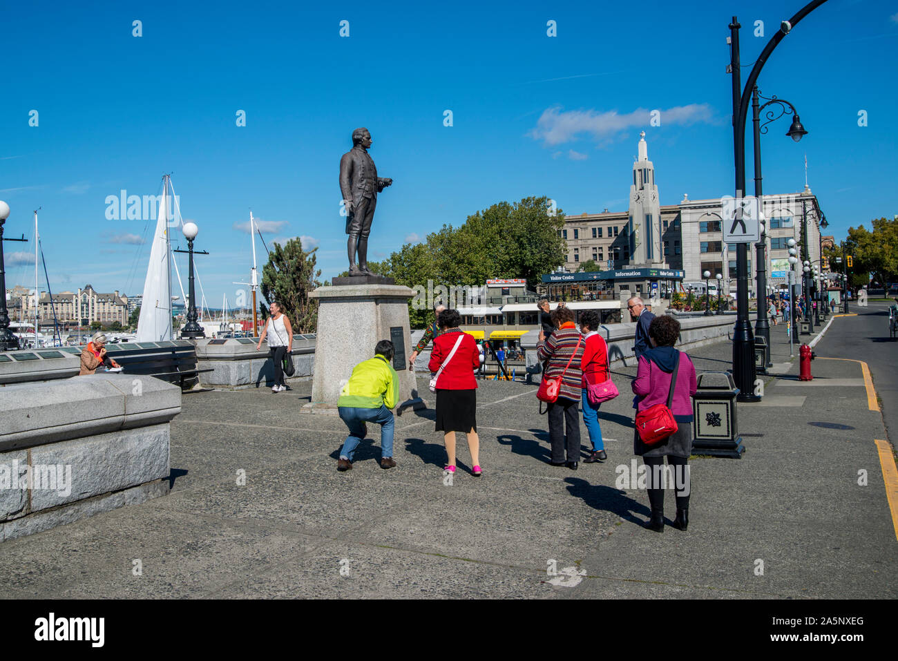Victoria, British Columbia, Kanada. Touristen, die Familie Bilder an der Statue von Captain James Cook im inneren Hafen Promenade. Stockfoto