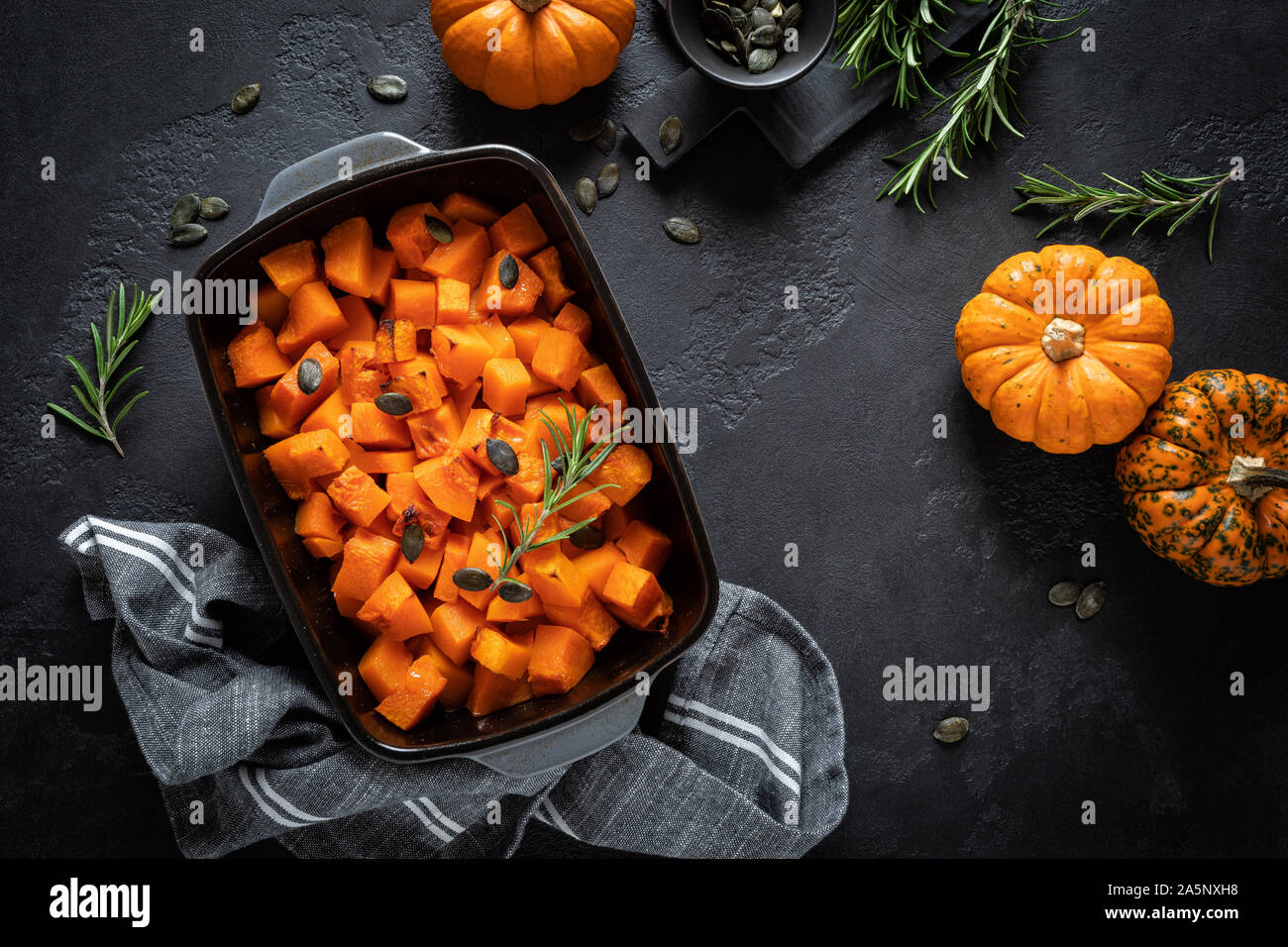 Gebratene Kürbisscheiben mit Rosmarin und Samen, gesunde, vegetarische Nahrung, Ansicht von oben Stockfoto