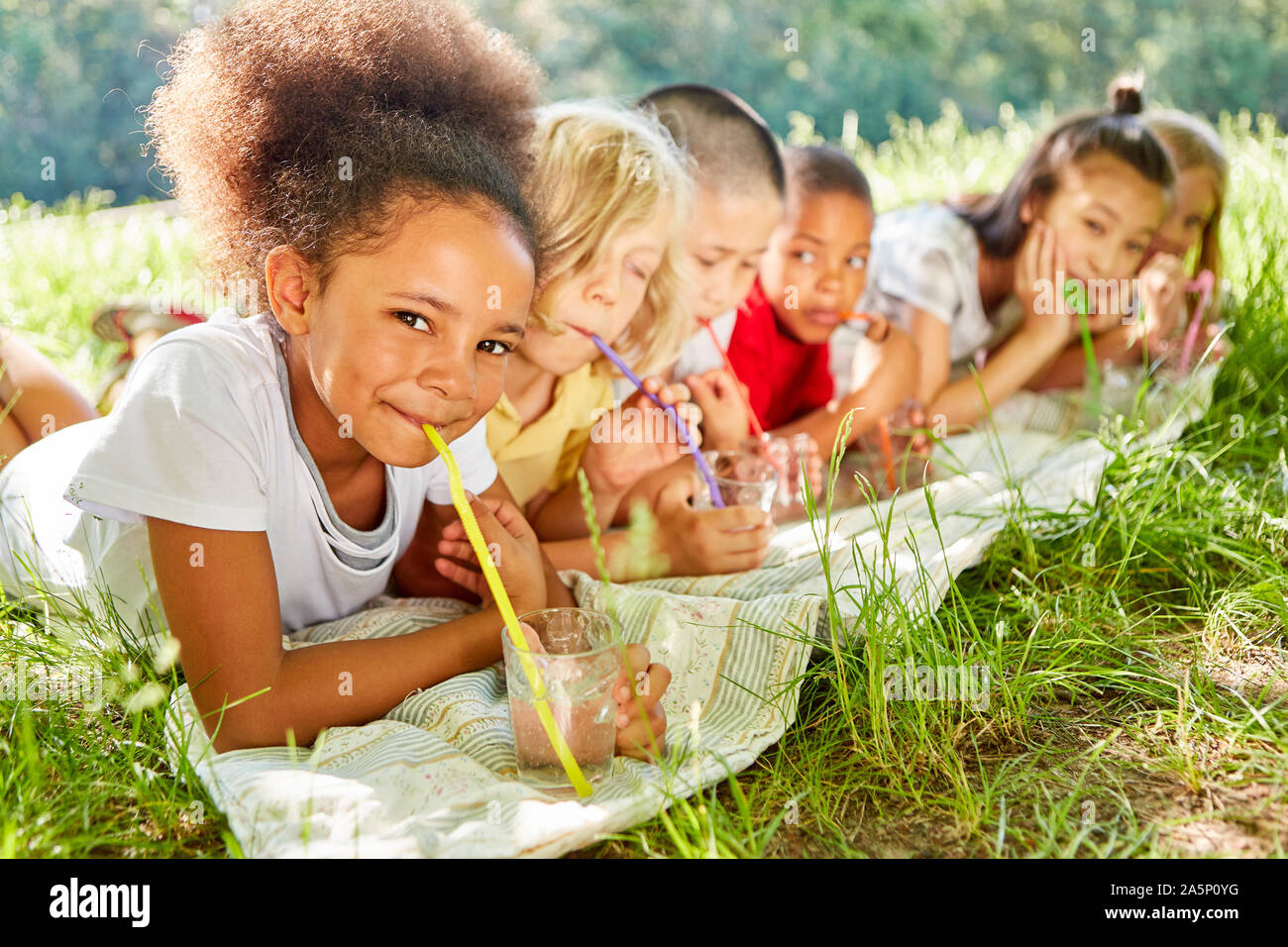 Multikulturelle Kinder Wasser trinken mit dem Strohhalm im Sommer in der Natur Stockfoto