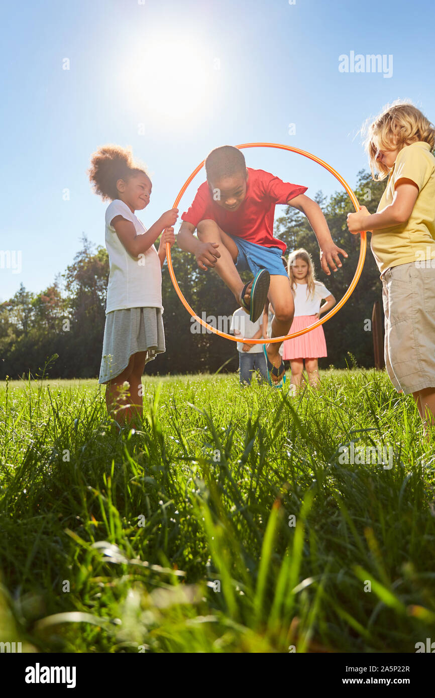 Kinder, Springen durch Reifen als Sport und Spielen im Sommer auf einer  Wiese Stockfotografie - Alamy