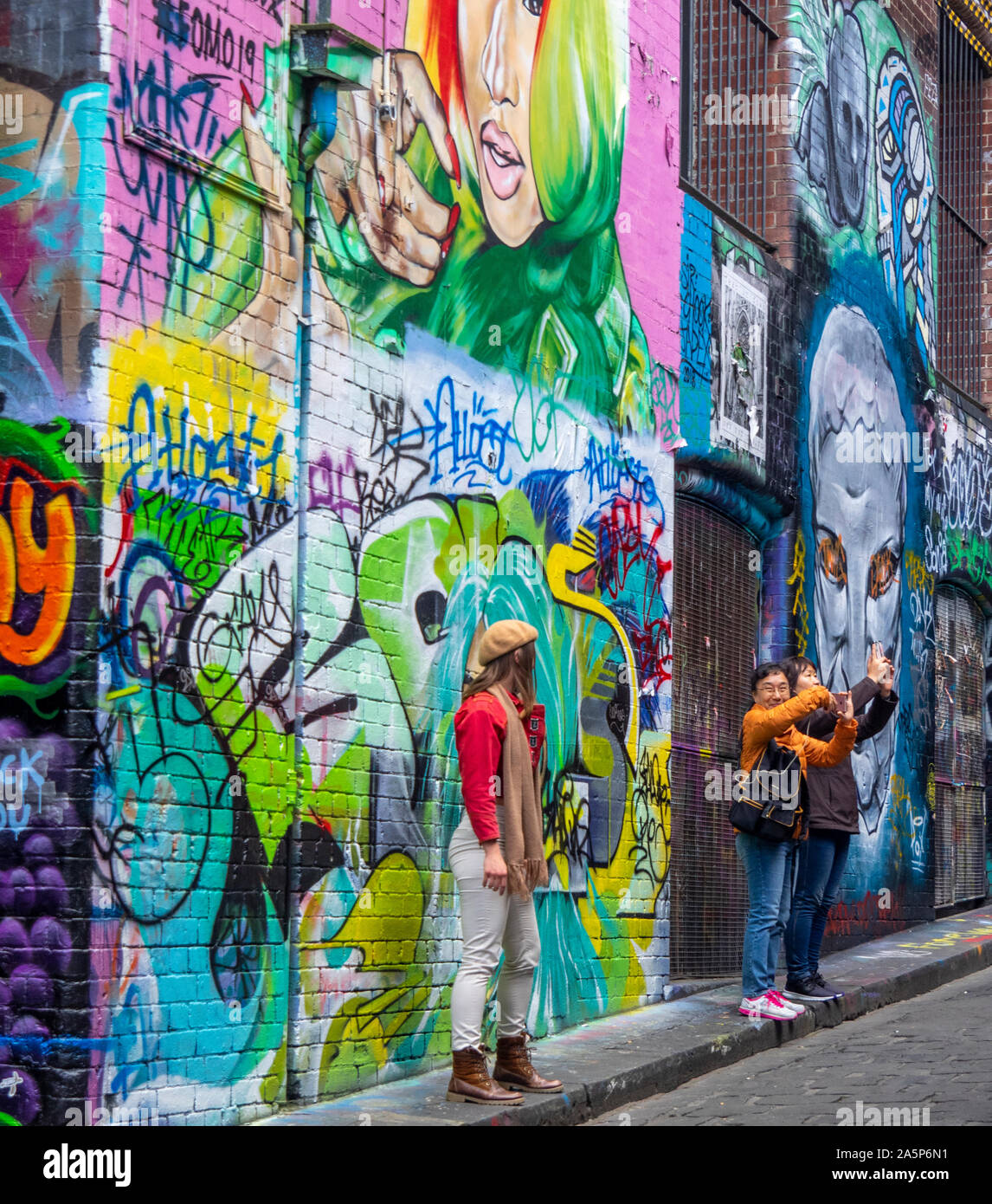 Frau auf der Suche nach Touristen fotografieren in Hosier Lane Wände in Graffiti und Street Art Melbourne Victoria Australien abgedeckt. Stockfoto
