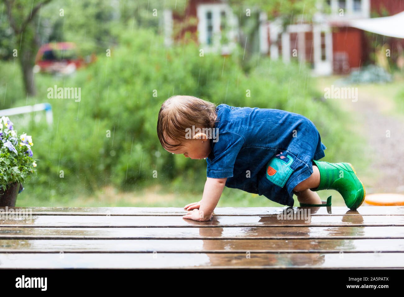 Kleinkind auf der Terrasse im Regen Stockfoto