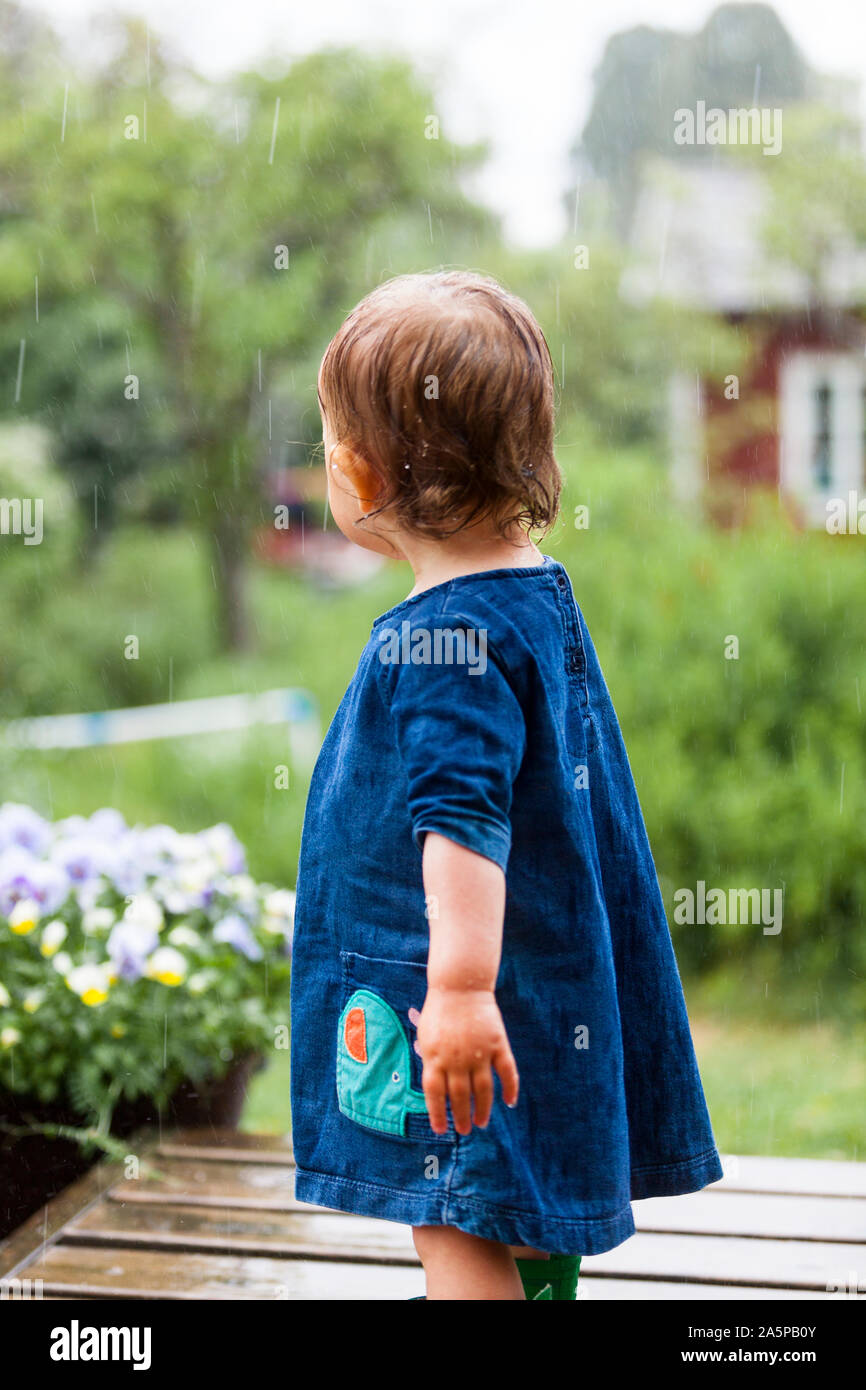 Kleinkind Mädchen auf Terrasse im Regen Stockfoto