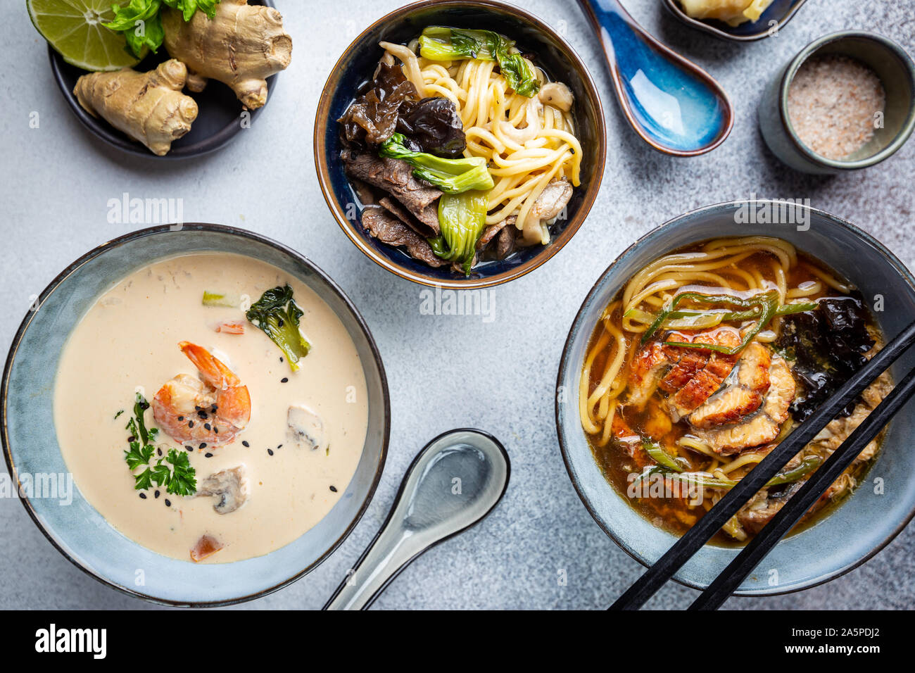 Satz serviert asiatische Suppen auf grauem Hintergrund der Ansicht von oben. Tom Yum Suppe, Aal Fischsuppe und Ramen Noodle Soup Stockfoto