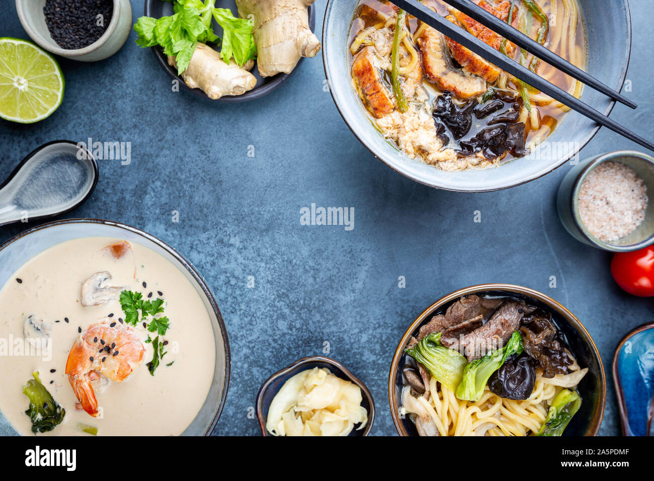 Satz serviert asiatische Suppen auf dunkelblauem Hintergrund der Ansicht von oben. Tom Yum Suppe, Aal Fischsuppe und Ramen Noodle Soup Stockfoto