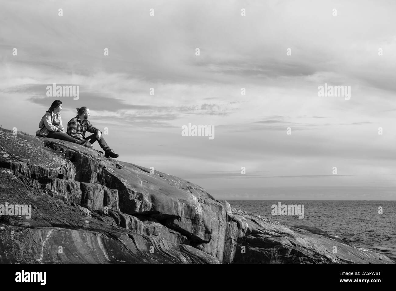 Paar sitzt auf Felsen und Meer Stockfoto