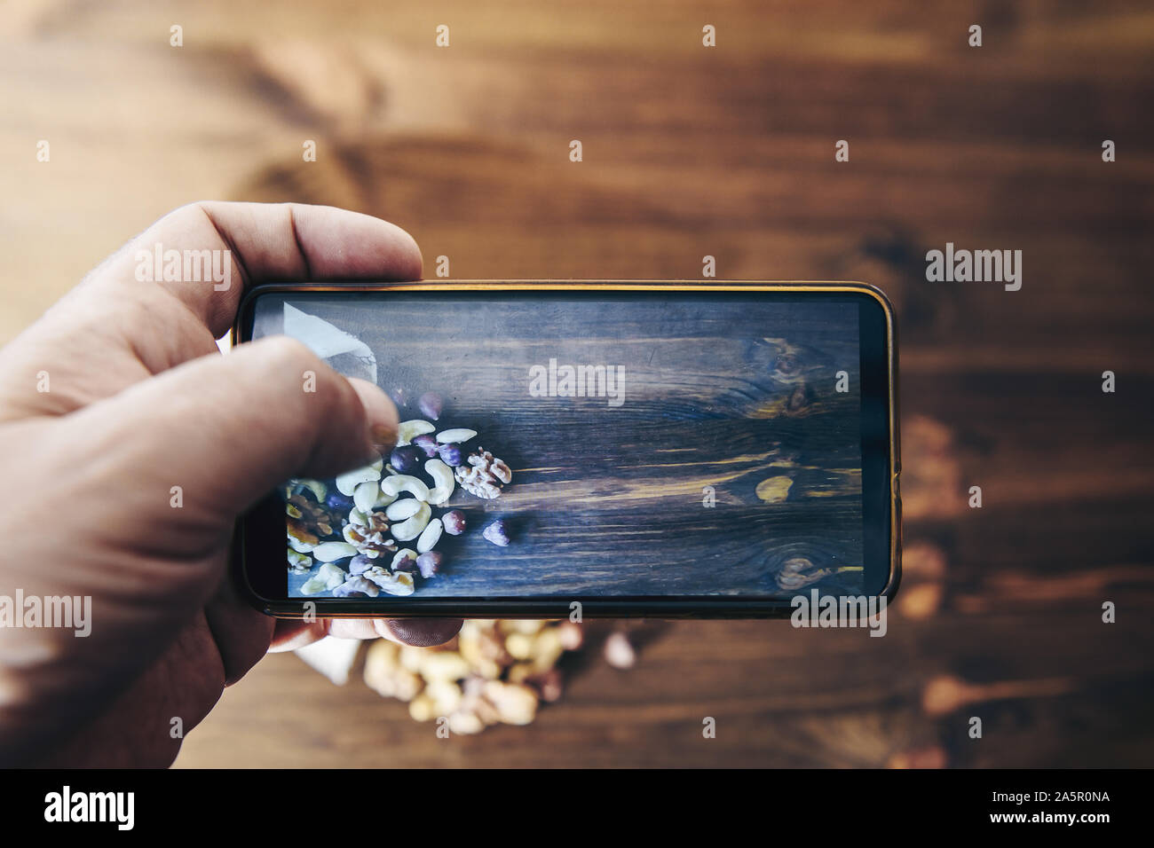 Essen blogger nimmt Foto für Blog, pic, Auswahl der vielfältigen Schalenfrüchte und getrocknete Früchte auf einem rustikalen Holztisch, gesunde Ernährung Konzept und vegetarischen Snack Stockfoto