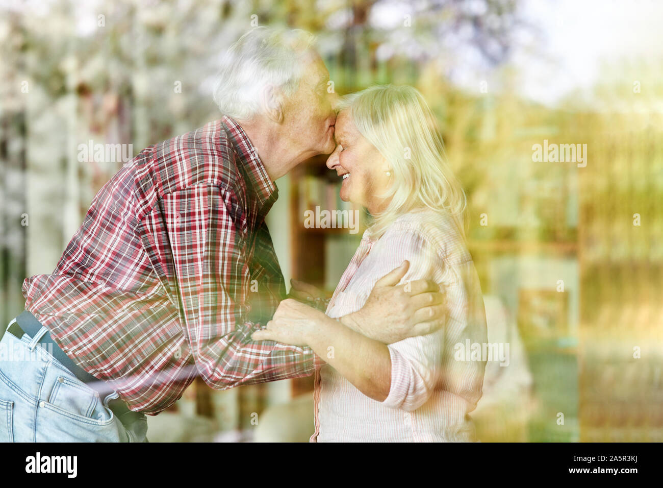 Senior küssen Stirn seiner Frau zärtlich als Zeichen der Liebe Stockfoto