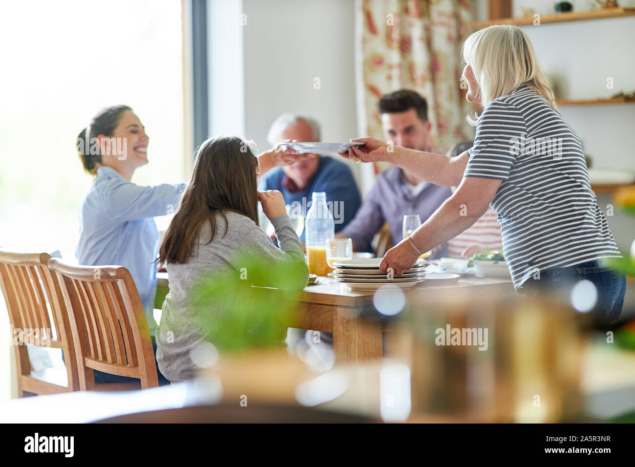 Glückliche Familie am Esstisch mit Mittag- oder Abendessen Stockfoto