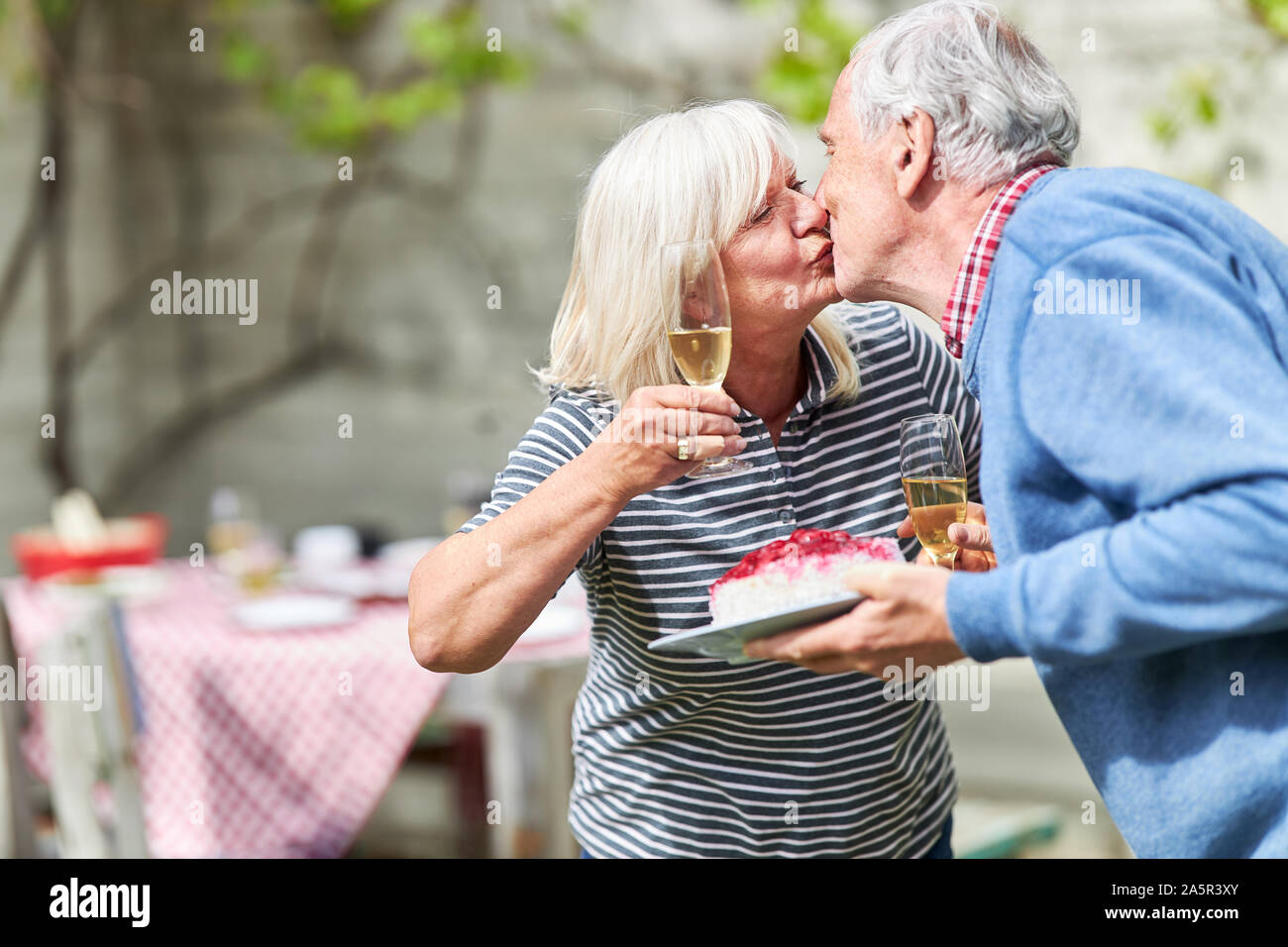 Paar der älteren Bürger auf eine Geburtstagsfeier oder eine Gartenparty küssen Stockfoto