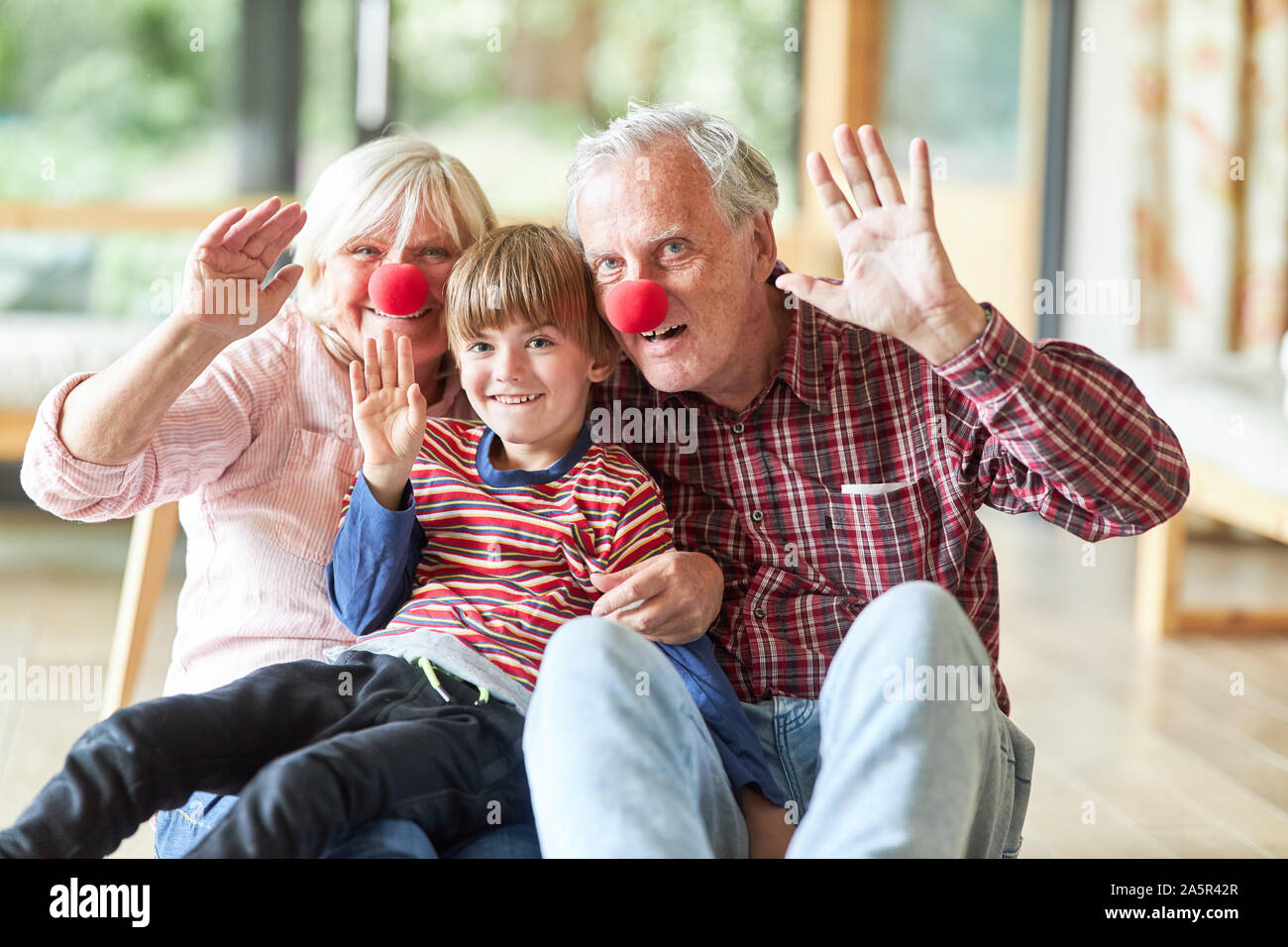 Großeltern und Enkel mit roter Clown Nase in Karneval oder Fasching Stockfoto